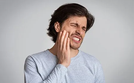 man in pain holding his face