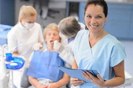 patient in dental chair with staff around them